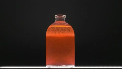 Strange and bubbling orange liquid chemical in pharmacy bottle Stock Footage 156264931