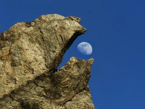 Strange beak-shaped rock eats the almost full moon Stock Photos
