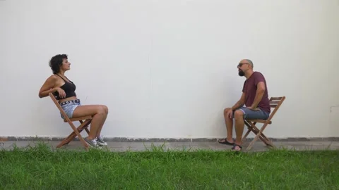 The strange couple sitting in front of the wall looks towards the camera 動画素材 138557311
