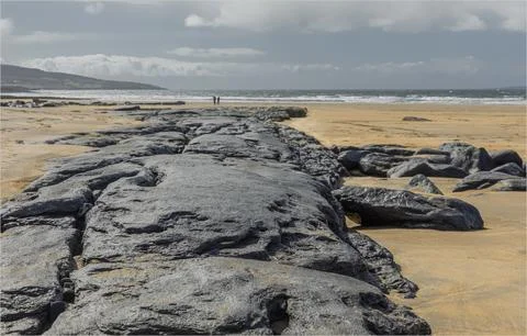 Strange dark stone limestone path on a beach Stock Photos