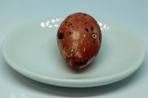 A strange face on an egg of quail in a red-orange range. Stock Photos