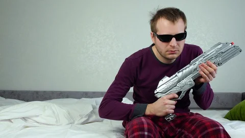 Strange man with black glasses pulls jerks foreend of toy blaster gun, shoots Stock Footage 129746936