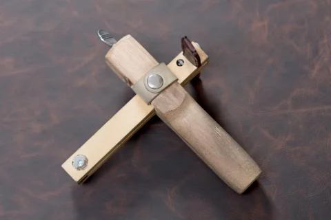 The strap cutter on brown leather background. Stock Photos