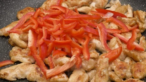 Straps of chicken fillet and thin straps of red pepper roasting on a frying pan 库存影片 290090190