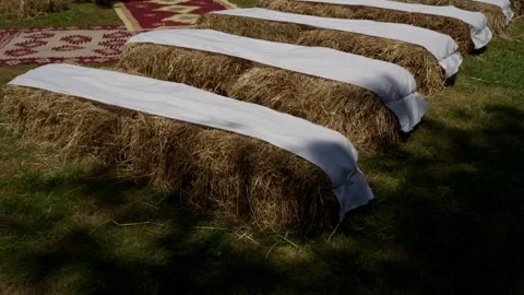 Straw bale benches with white cloth set on grass for outdoor ceremony Stock Footage 346154561
