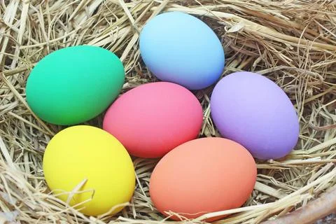 Straw basket with easter eggs on wooden background Stock Photos