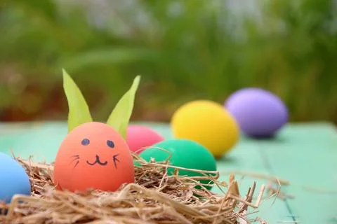 Straw basket with easter eggs on wooden background Stock Photos