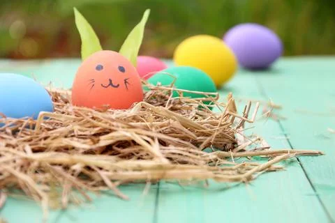 Straw basket with easter eggs on wooden background Stock Photos