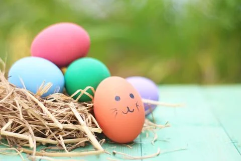 Straw basket with easter eggs on wooden background Stock Photos