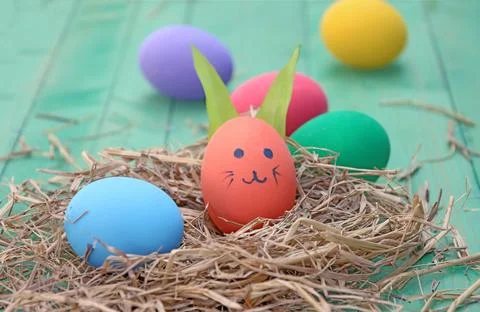 Straw basket with easter eggs on wooden background Stock Photos