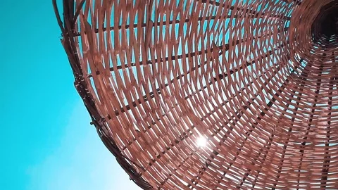 Straw beach umbrella and blue sky view. Sunlight shining through the umbrella  스톡 동영상 109411989