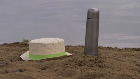 Straw hat and flask on sand beach Stock Footage 153513244