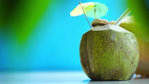 Straw hat and fresh young coconut with straw and little umbrella ready for drink Stock Footage 147044934