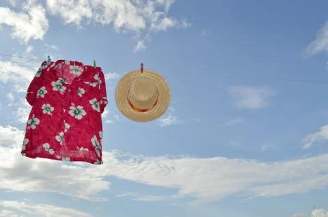 Straw hat and hawaii shirt  on clothesline Stock Photos
