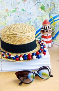 Straw hat, beads, ceramic lighthouse against map Stock Photos