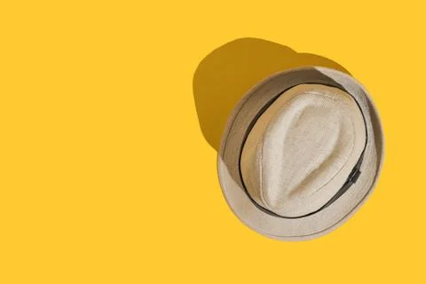Straw hat on bright yellow background with hard shadow. Sun protection in the Stock Photos