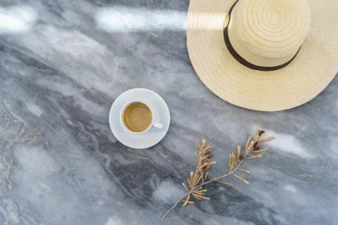 Straw hat, dry olive tree branch with olives, coffee cup on marble grey table Stock Photos