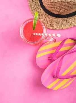 Straw hat, fli flops and red smoothie on pink Stock Photos
