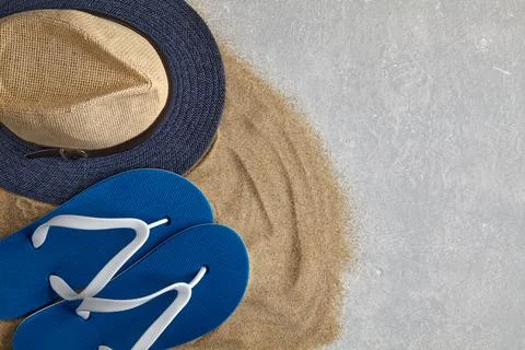Straw hat, flip flops on scattered sea sand Stock Photos