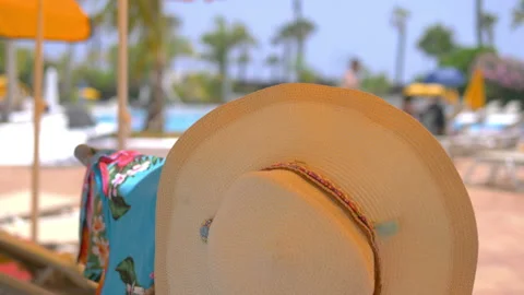 Straw hat hanging on sunbed in summer in 4k slow motion 60fps Stock Footage 113928413