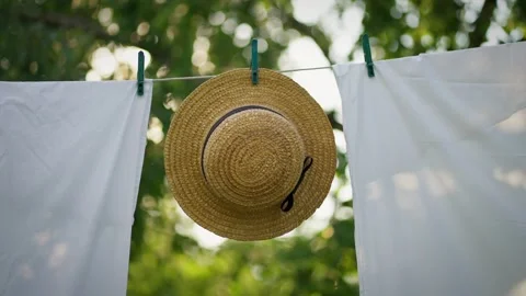 Straw hat hangs on clothesline in garden. Summer vacation concept Stock Footage 276328000