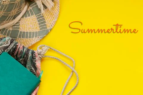 Straw hat, notepad, backpack and Summertime text on bright yellow background Stock Photos
