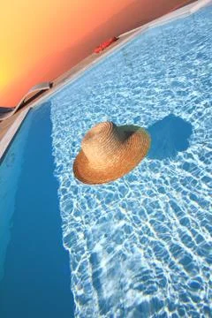 Straw hat in the pool. End of summer concept Stock Photos