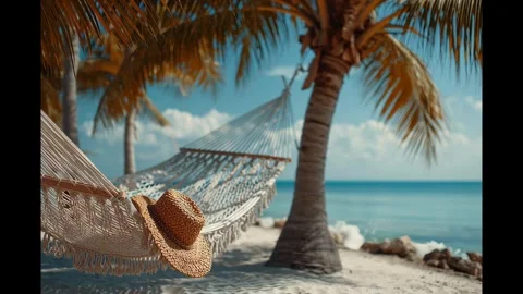 Straw hat resting on a white hammock between palm trees on a sandy beach Stock Footage 328499158