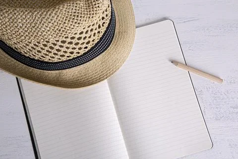 Straw hat on small notebook with blank pages Stock Photos