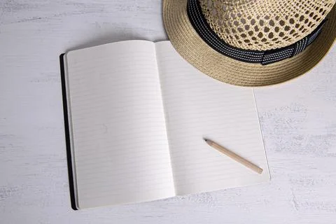 Straw hat on small notebook with blank pages Stock Photos
