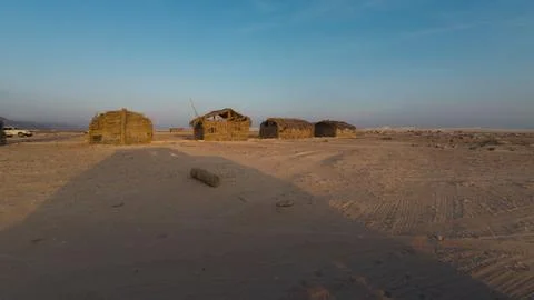 Straw huts on a sandy desert plain at sunset Stock Photos