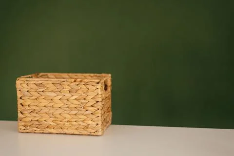 Straw rectangular basket on a background of a green wall 스톡 사진