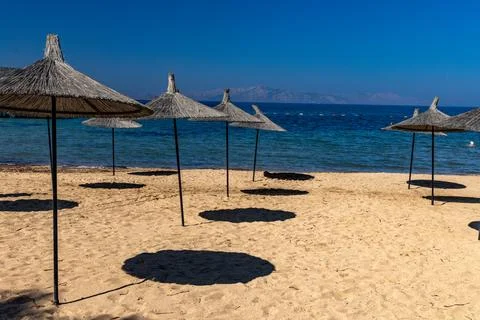Straw sun umbrellas placed on the beach on the Aegean Sea in Turgutreis, Tu.. Stock Photos