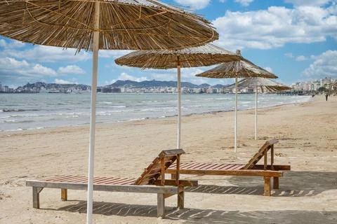 Straw umbrella an beach chairs on a empty seaside beach. Stock Photos