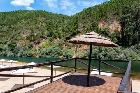 Straw umbrella on river beach Stock Photos