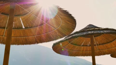 Straw umbrellas view on sunset. sunset with flare from straw umbrellas. summer  Stock Footage 245996369