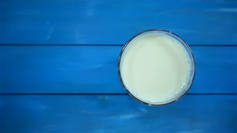 Strawberrie falling in slow motion in a full glass of milk on a blue Video stock 134004747