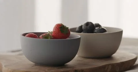Strawberries and blueberries in bowls on wood table Stock Photos