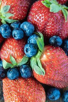 Strawberries and blueberries lined up on rustic background, top view. Stock Photos