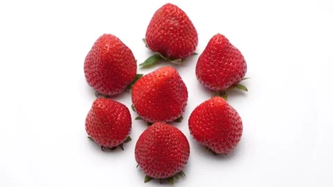 Strawberries arranged in a circular pattern rotate against a clean white Video stock 310805114