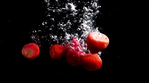 Strawberries fall into the water on a black background of bubbles slow motion Stock Footage 176389709