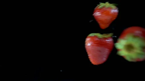 Strawberries falling in slow motion on a wet black Stock Footage 137787531
