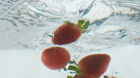 Strawberries falling into the water with bubbles in an aquarium 120 fps Stock Footage 101686656