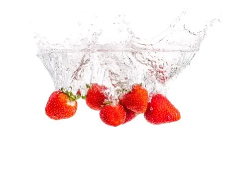 Strawberries falling into water causing bubbles all around it. Healthy food c Stock Photos