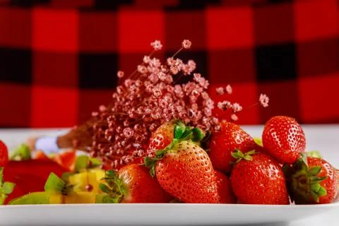 Strawberries with flowers on red background. Stock Photos