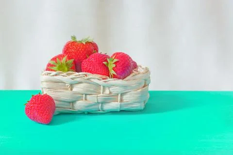 Strawberries in front of a basket on a turquoise table, selective focus Stock Photos