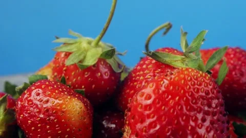 Strawberries with green branches on a blue background rotating in a circle... Stock Footage 283391102