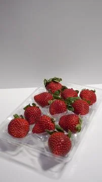 Strawberries in a plastic container on a white background. Stock Photos