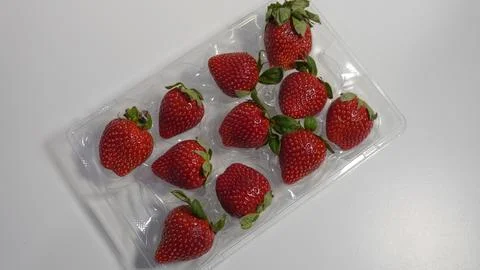 Strawberries in a plastic container on a white background. Stock Photos