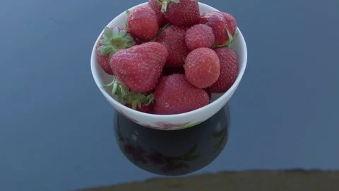 Strawberries in a plate on a mirror table. The camera is slowly approaching. Stock Footage 77576230